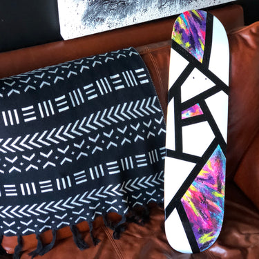 hand painted abstract art on a skateboard sitting on a leather couch