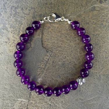 Amethyst 8mm beads bracelet with sterling silver lobster clasp. Has one accent sterling silver wave bead.