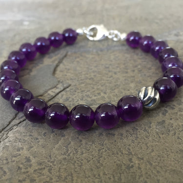 Amethyst 8mm beads bracelet with sterling silver lobster clasp. Has one accent sterling silver wave bead.