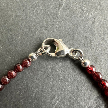 close up of lobster clasp made from sterling silver with garnet beads for a mens bracelet