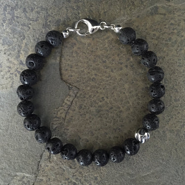 Black lava 8mm beads has smooth surface but dotted by countless tiny holes. Has one accent sterling silver wave bead.