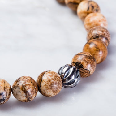 A close-up of a Picture jasper 8mm bead bracelet with one accent sterling silver wave bead. With Sterling silver components and a lobster clasp.