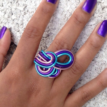Turquoise, pink, and purple anodized aluminum wire wrap ring.
